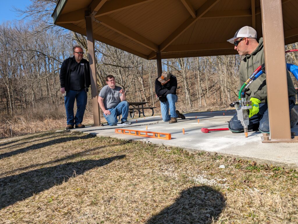 Operator leveling concrete with onlookers